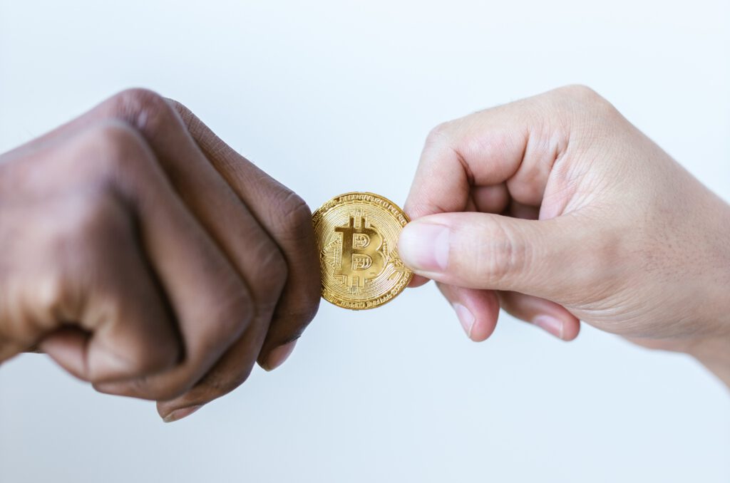 twee handen met tussenin een gouden bitcoin munt