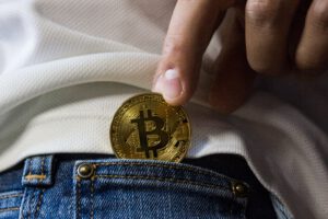 gouden bitcoin munt in hand bij broekzak