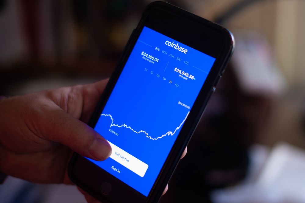 telefoon in hand met op het scherm een overzicht van coinbase